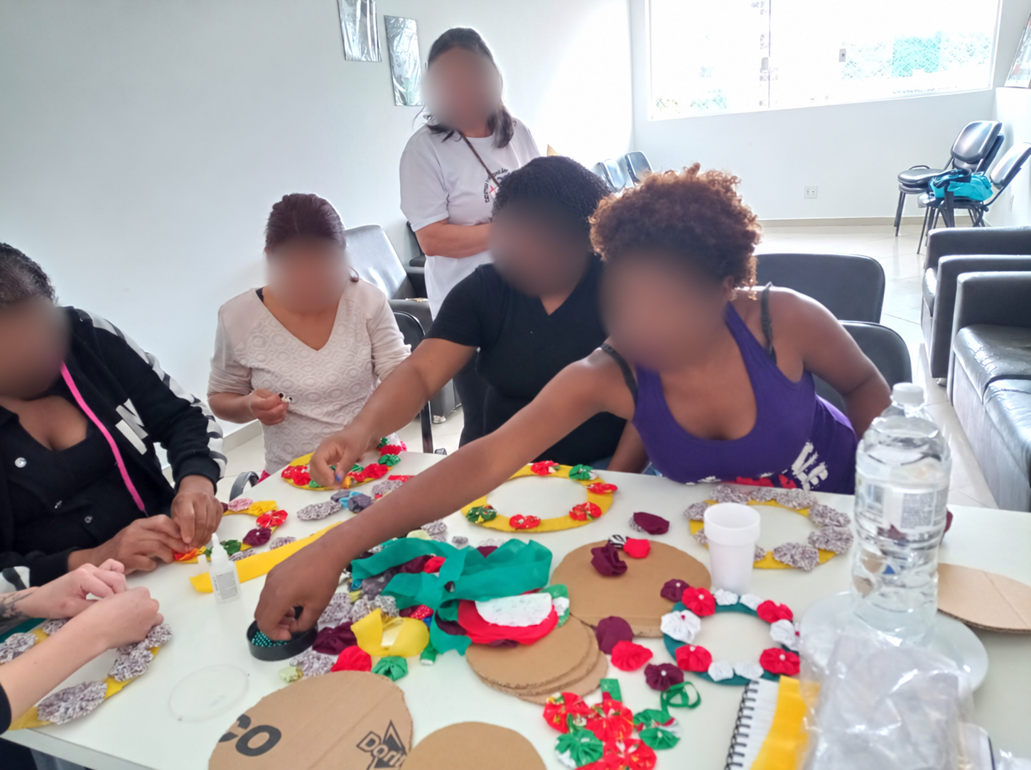 Participantes com rostos borrados criando peças com fuxicos coloridos